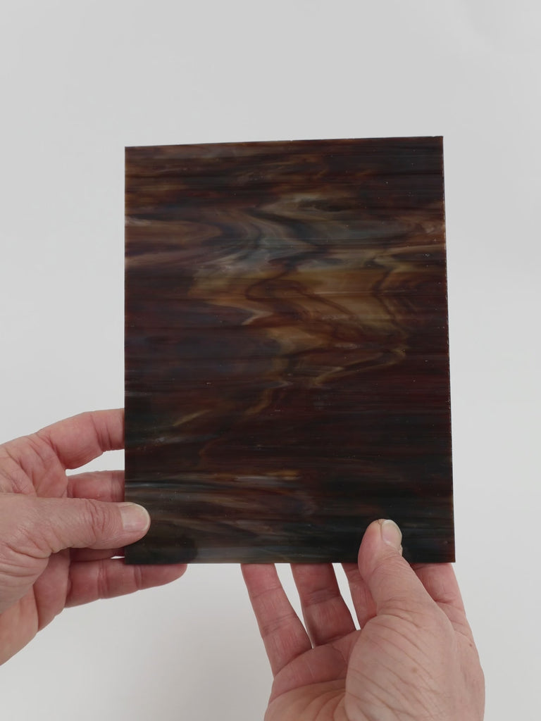 Video of the Charred Bark glass plate in opaque brown, 15x19cm, held up and tilted to show its pattern and transparency
