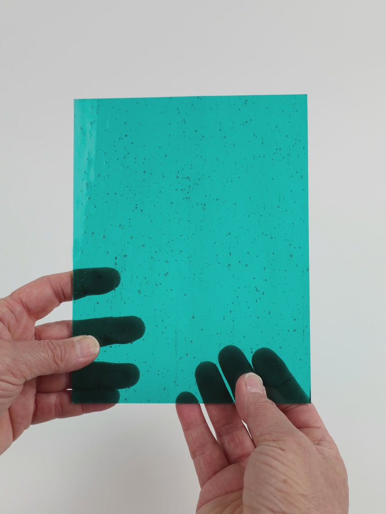 Video of the Teal glass plate in transparent teal, 15x19cm, held up and tilted to show its pattern and transparency