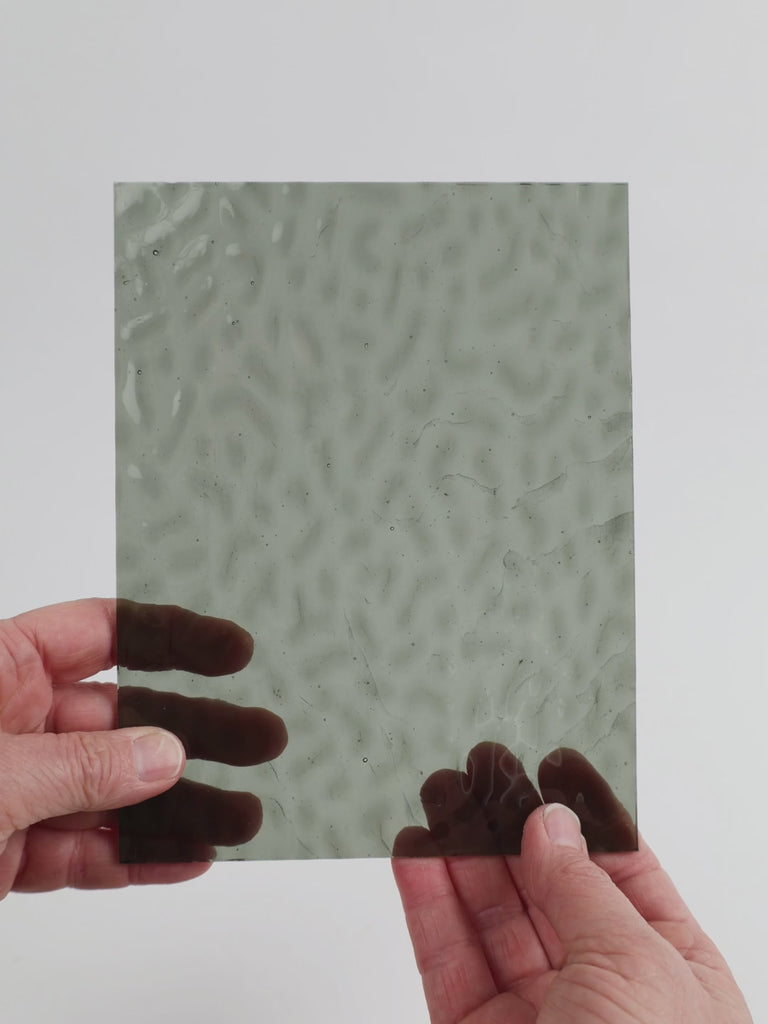 Video of the grey ripple glass plate in grey transparant mottle, 15x19cm, held up and tilted to show its pattern and transparency